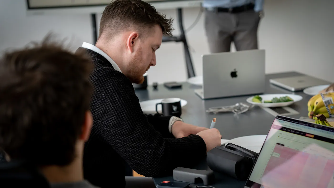 Ein Kollege arbeitet mit Notizen und Laptop am Besprechungstisch